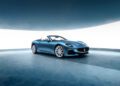 A sleek GranCabrio in striking blue is showcased under a curved ceiling in a minimalistic, modern showroom with a reflective blue floor, reminiscent of the elegance found at I.C.E. St. Moritz.