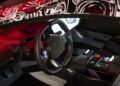 Futuristic car interior with a steering wheel, digital displays, and illuminated controls, featuring a black and red color scheme and patterned roof reminiscent of the cutting-edge design seen in the BMW Vision series.
