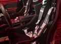 The interior of the car boasts racing seats and harnesses, with a dashboard brimming with controls. Red ambient lighting accentuates the detailed design reminiscent of BMW Vision's cutting-edge EV tech.