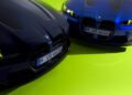 Two blue BMW M4 CS cars with illuminated headlights are parked on a bright green surface, echoing the dynamic spirit of VR46.