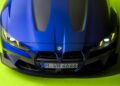 Top view of a sleek blue BMW M4 CS with illuminated headlights, set against a vibrant green background—a fitting tribute for Valentino Rossi's 46th birthday celebration.