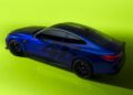 A sleek blue sports car, the BMW M4 CS VR46 edition, with black wheels and the iconic number 46 on its side, sits impressively on a bright green surface—a tribute to Valentino Rossi's celebrated legacy.