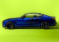 Side view of a blue BMW M4 CS sports car with the number 46 on the door, set against a bright yellow background, paying homage to racing legend Valentino Rossi.
