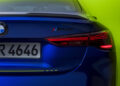 In celebration of Valentino Rossi's 46th birthday, a sleek blue BMW M4 CS with VR 4646 plates showcases its illuminated taillights against a vibrant greenish-yellow backdrop.