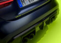 Close-up of a BMW M4 CS VR46's rear bumper and exhaust, flaunting a sleek black finish with Valentino Rossi's iconic "VR46" logo and license plate, set against a vibrant green background.