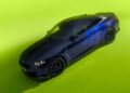 A sleek black BMW M4 CS adorned with blue number 46 decals, reminiscent of VR46 and the legendary Valentino Rossi, is parked on a vibrant lime green surface.