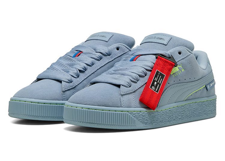 A pair of light blue PUMA sneakers with green accents, thick laces, and a red tag attached to one shoe, these automotive-inspired kicks bring sporty style to any driver’s look.
