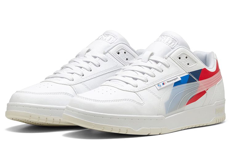 A pair of white PUMA sneakers with blue and red accents on the side and a cream-colored sole, shown on a white background—these automotive-inspired kicks are perfect for those seeking the best driver shoes.