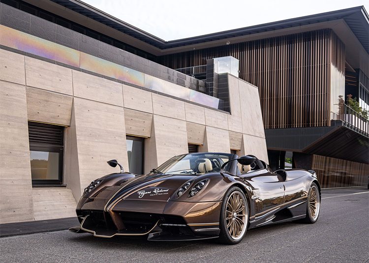 A brown luxury sports car is elegantly parked in front of a modern building with wooden accents, reminiscent of the sophisticated style found at Asia's exclusive Magarigawa Club.