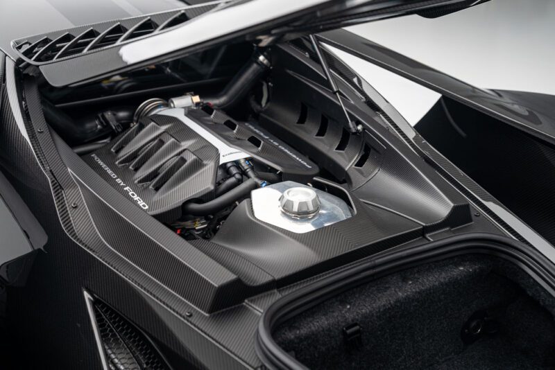 Close-up of a Ford GT engine with a carbon fiber cover and metallic components, set in the sleek Liquid Carbon Edition design featuring ghosted stripes.