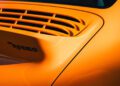 A close-up of an orange car's rear section features a vent and the bold text "RUF Rodeo" in black, making for a unique display.