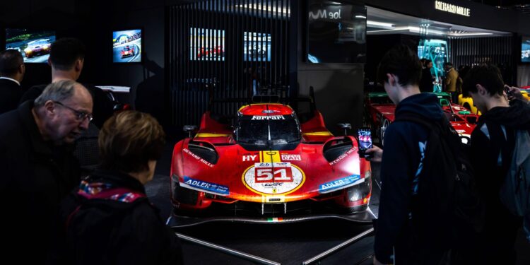 A red racing car with the number 51 is displayed at the Rétromobile USA auto show in New York City. In November 2026, enthusiasts gather around, eager to capture photos of this stunning machine.
