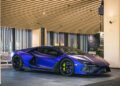 A sleek, blue sports car with black details sits parked indoors under a wooden ceiling, poised for the thrilling speeds of Asia's first $200M race circuit at the exclusive Magarigawa Club.