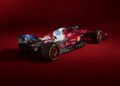A red and white SF-25 F1 Car adorned with various sponsor logos is shown against a matching red background. Ferrari unveils this striking vehicle, positioned to display a captivating rear side view.