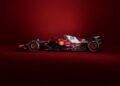 A striking SF-25 Formula 1 racing car in vibrant red and brown is showcased against a bold red backdrop, adorned with logos and sponsorship decals that celebrate its Ferrari heritage.