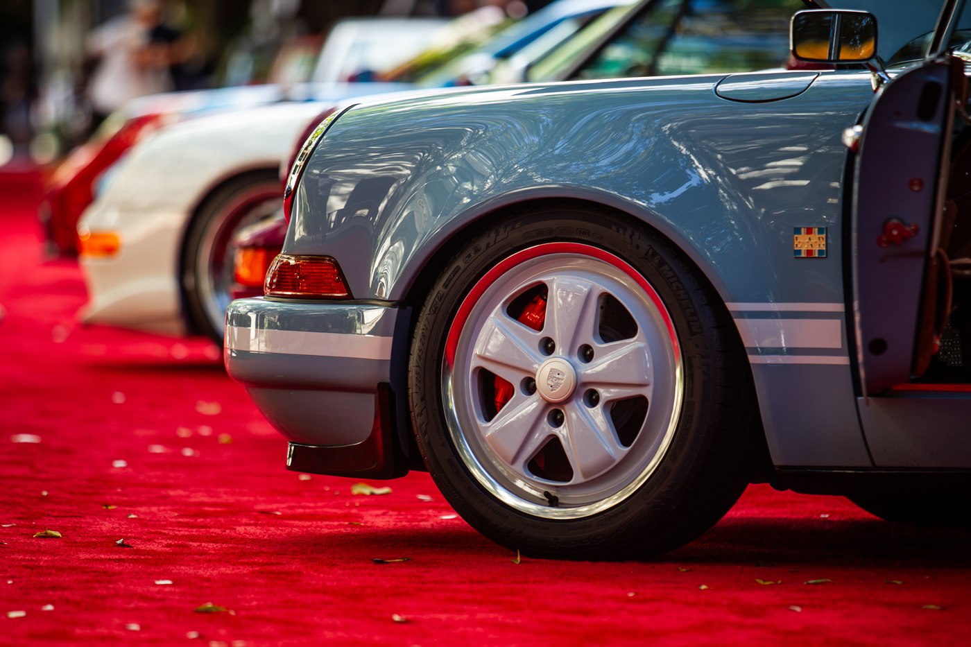 At the Miami Concours 2025, classic cars grace the red carpet with elegance, their gleaming rear wheels and fenders capturing the essence of automotive art.