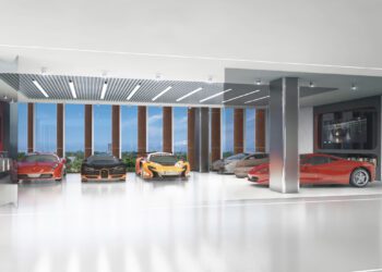 A modern showroom in a luxury tower displays six Pininfarina-designed sports cars in a sleek, well-lit interior with large windows and framed photos on the wall.