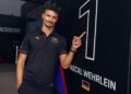 A man stands proudly beside a board displaying the number 1 and "Pascal Wehrlein," celebrating a triumphant moment in Miami amid the thrilling Porsche Formula E scene.