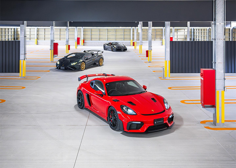 Three sleek sports cars in a parking garage: a red one catches the eye in the foreground, while black and dark gray models linger behind. These beauties await their next thrill at Asia's first-ever private members-only race circuit, the prestigious Magarigawa Club.