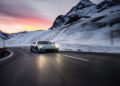 A Rimac sports car makes its debut appearance, speeding down a snowy mountain road at dusk, with the colorful sunset painting a perfect backdrop reminiscent of I.C.E. St. Moritz's exclusive charm.