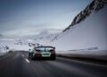 A Rimac sports car, showcasing its debut appearance, powers through a snowy mountain road under a cloudy sky at I.C.E. St. Moritz, its large rear wing cutting through the crisp alpine air.