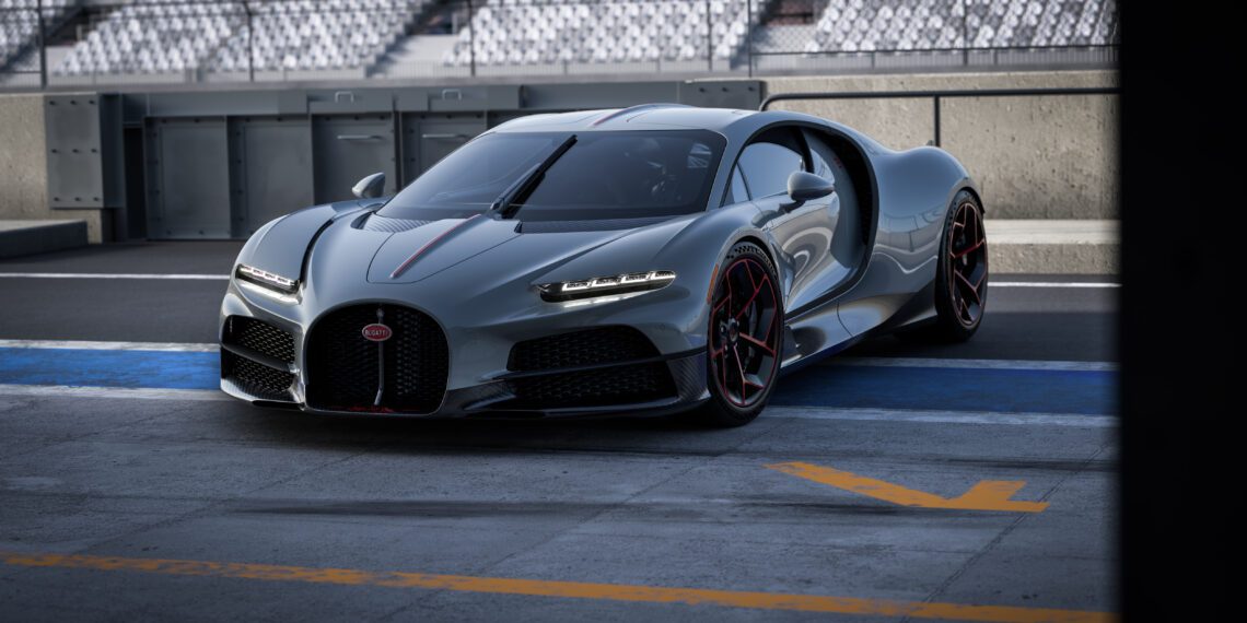 A sleek gray sports car with a streamlined design, bearing the prestigious Équipe Pur Sang emblem, is parked on a race track. The Bugatti flaunts black and red accents, situated near empty spectator stands.