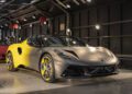 A sleek, matte-finished Lotus sports car with a Union Jack design on the front bumper, parked indoors under bright lights.