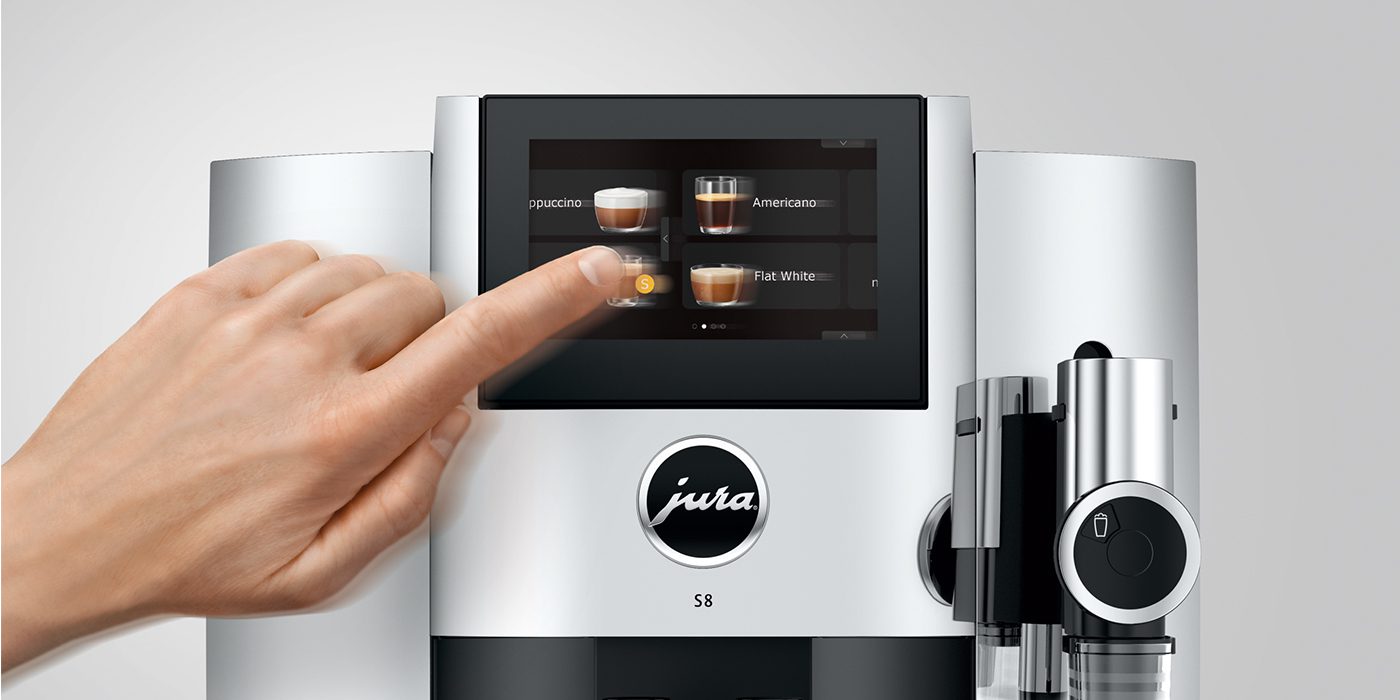 A person indulges in coffee enjoyment by selecting a brew on the innovative digital touch screen of a JURA S8 coffee machine.