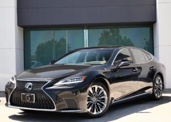 A black Lexus sedan, one of the top affordable luxury cars, is parked in front of a modern building with large glass windows.