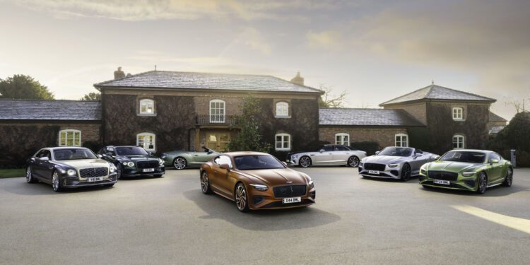 A group of luxury 2024 Bentleys is parked in front of a large stone house on a cloudy day.