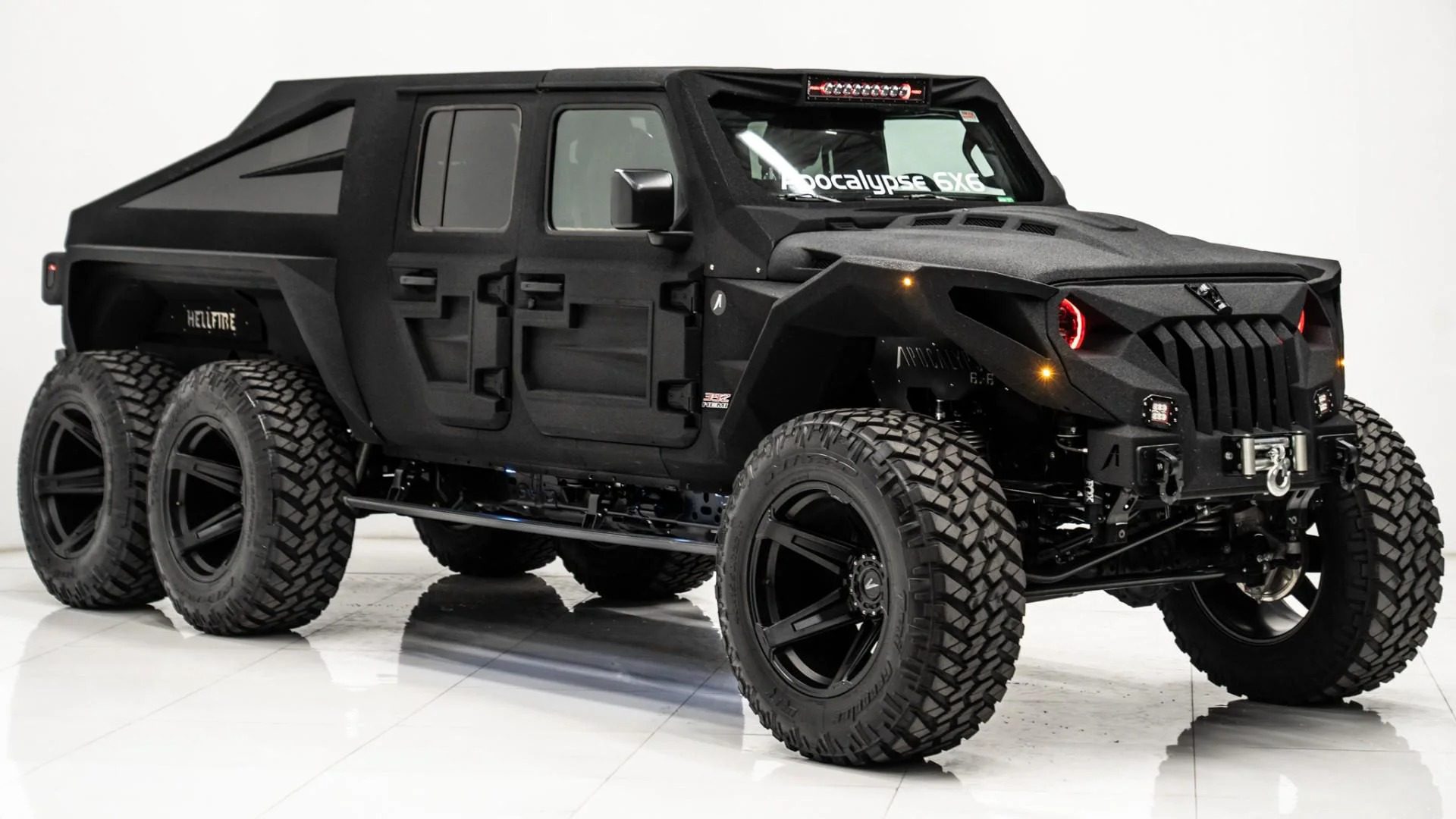 Matte black six-wheeled off-road 6x6 truck with large tires, angular body design, and LED headlights shown in a brightly lit studio setting—perfect for those searching for unique 6x6 trucks for sale.