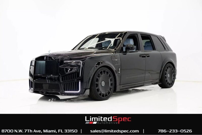 A matte black Rolls-Royce Cullinan, the pinnacle of luxury SUVs, is parked in a well-lit studio with branding and contact details for Limited Spec Automotive displayed at the bottom.