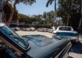 Vintage and modern cars parked under trees in a sunny lot, featuring a silver Mercedes-Benz sports car in the foreground, reminiscent of the style you'll see at ModaMiami 2025.