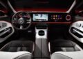 Interior view of the New CLA Mercedes-Benz showcasing a sleek steering wheel, a dashboard with groundbreaking tech and digital screens, luxurious two-tone seats, and soothing ambient lighting.