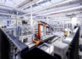 In an industrial factory setting, a robotic arm enhanced with AI operates seamlessly on the assembly line, surrounded by advanced machinery and equipment.