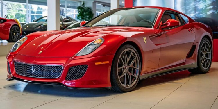 A red Ferrari 599 GTO, a must-have for any supercar collection, is displayed in a showroom with large windows and other cars in the background.