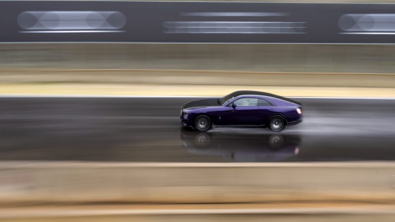 A purple Black Badge Spectre speeds along a wet racetrack, creating a motion blur effect.