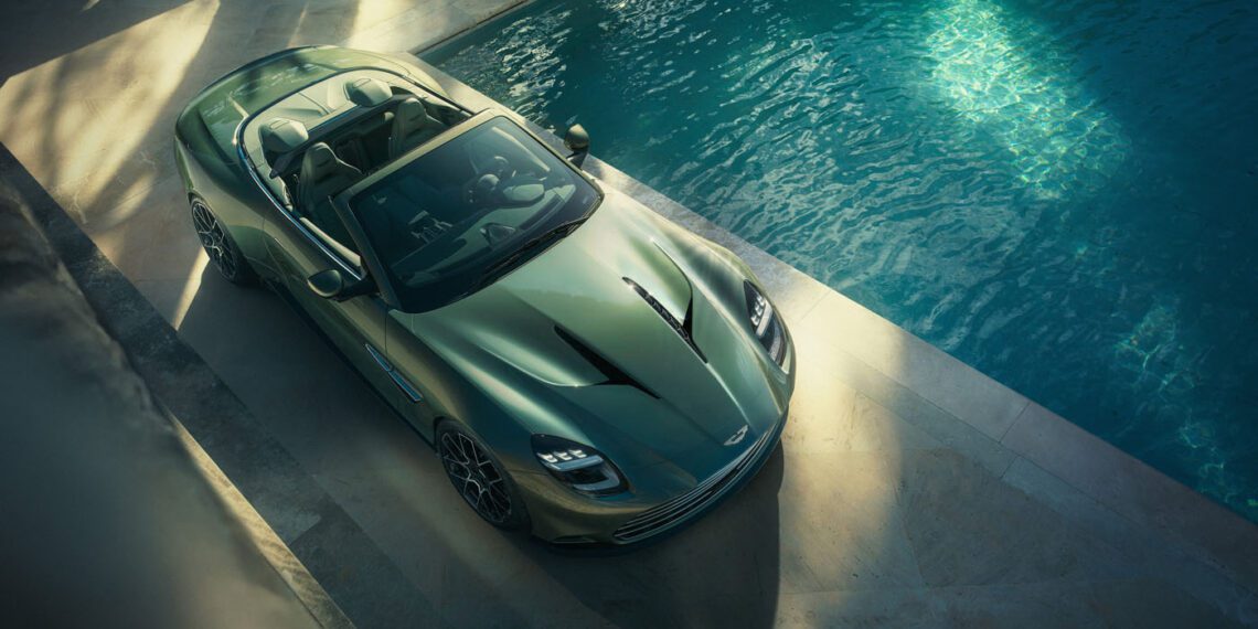A sleek Aston Martin Vanquish, the fastest front-engined convertible, sits elegantly beside a pool, with the sun casting enticing shadows over its luxurious curves.