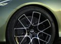 Close-up of a car's front wheel with a sleek alloy design and continental performance tire, set against the green body of an Aston Martin Vanquish, the fastest front-engined convertible.