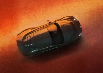 A shiny, black sports car is viewed from above, parked on a textured, orange surface with subtle lighting highlighting its sleek design.