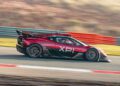 The red and black high-performance car, labeled "XP1", races down the Goodwood track, its speed emphasized by a masterstroke of automotive design blur.