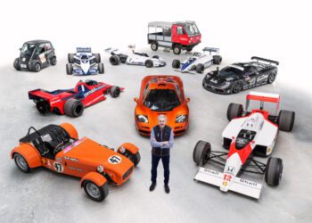A person stands in front of a diverse lineup of vehicles, featuring race cars, a sports car, a microcar, and a small truck—each a testament to innovative automotive design—all displayed on a pristine white background.