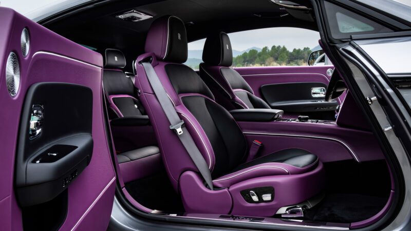 Car interior with purple and black leather seats and trim. The open door reveals the front and rear seating areas. The dashboard and steering wheel are partially visible.