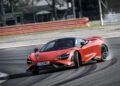 A red LT Cars sports car drifts around a racetrack corner, emitting slight tire smoke.