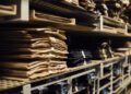 Shelves filled with neatly stacked piles of various colored fabric swatches resemble the meticulous precision seen in crafting a Rolls-Royce, where every detail is honed to perfection.