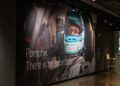 A large poster of a race car driver wearing a helmet with a blue visor at the Porsche Experience Center, Atlanta. Text reads: "Porsche. There is no substitute.