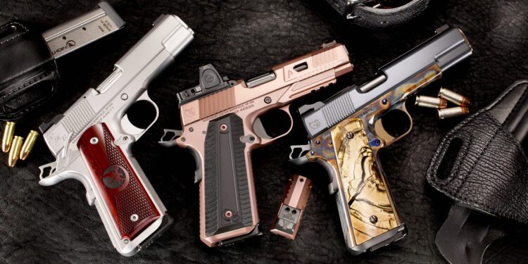 Three Nighthawk Custom handguns with detailed grips are displayed on a dark surface, surrounded by magazines, bullets, and a leather holster.