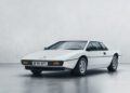 A white vintage Lotus sports car is parked in a minimalistic setting with a plain background, evoking the sleek and innovative spirit often seen at Milan Design Week.