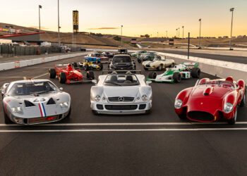 A stunning lineup of vintage and classic racing cars graces the track at sunset during the vibrant Motorsport Festival, showcasing an eclectic mix of styles and colors.