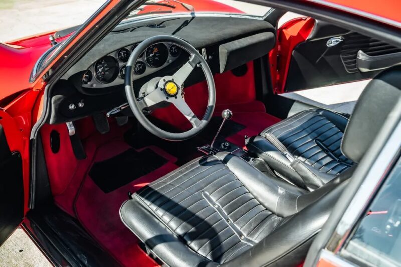 Interior mobil sport merah klasik ini, yang berpotensi menjadi Ferrari Dino 246 GT, menawarkan kursi kulit hitam, roda kemudi tiga-spoke, dan alat pengukur analog. Dengan shifter peralatan manualnya, para penggemar akan menghargai keanggunannya yang abadi - sempurna untuk lelang Sotheby Motorsport yang akan datang.